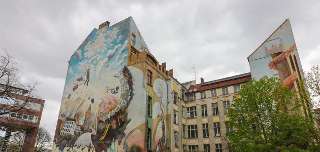 Das Bild zeigt eine bunt bvemalte Hausfassade in Berlin-Neukölln