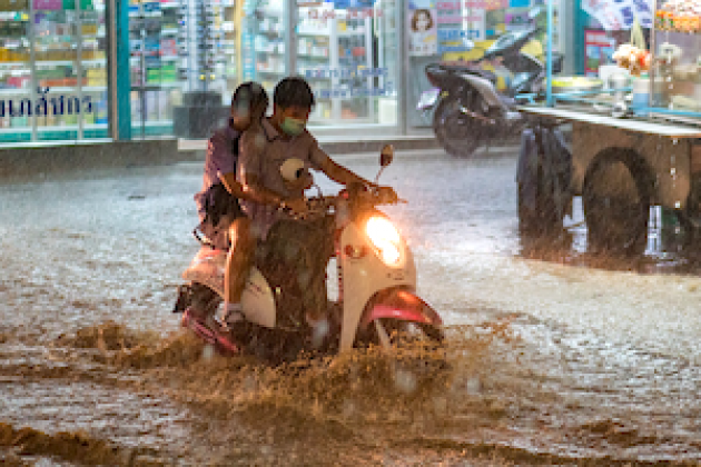 Ein Mopedfahrer auf einer überschwemmten Straße
