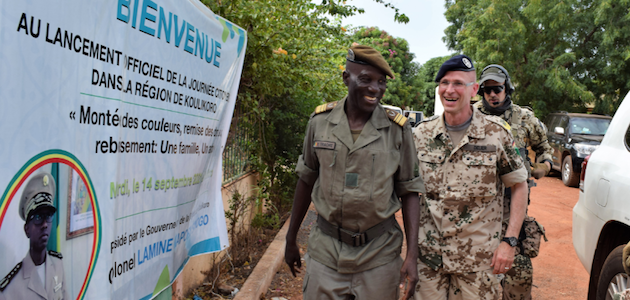 Ein malischer und ein deutscher Soldat vor einem Plakat in Mali.