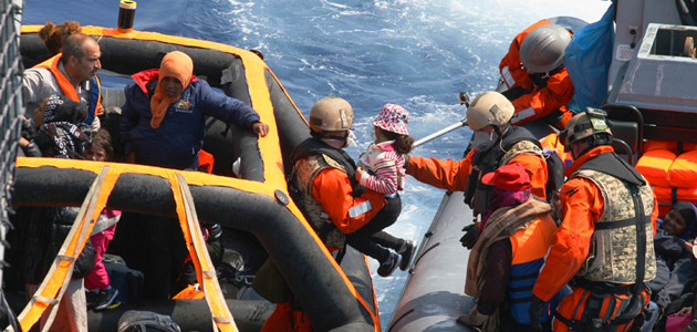 Aus einem Speedboat der Marine reichen deutsche Marinesoldaten ein Flüchtlingskind auf eine Rettungsinsel, die als Einstieg zu einem größeren Schiff dient.