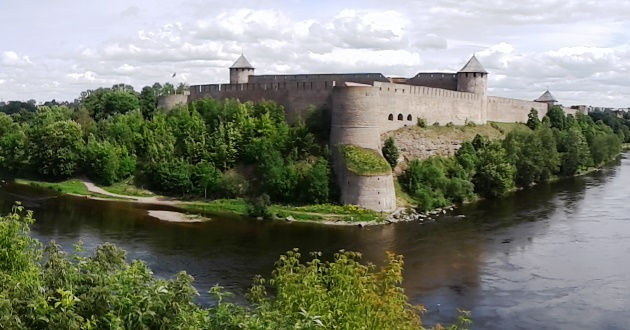 Eine Burg umgeben vorm Wasser vor bewölktem Himmel.