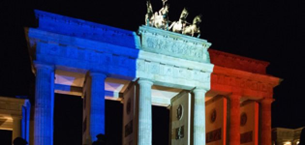 Nachtaufnahme des Brandenburger Tors, das in den französischen Nationalfarben Blau-Weiß-Rot angestrahlt wird.