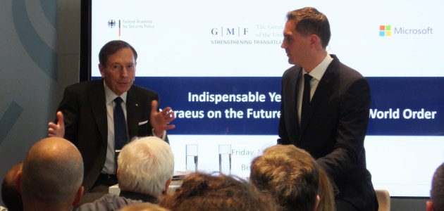 David Petraeus diskutiert vor einem Bildschirm, der die Logos der BAKS, des German Marshall Fund und Microsoft zeigt, mit dem Journalist Frederik Pleitgen.