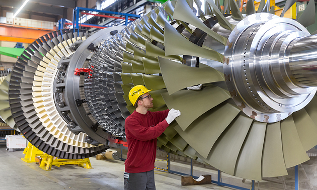 Foto: Siemens AG In einer Werkshalle inspiziert ein Mitarbeiter der Siemens AG die Schaufeln einer großen Gasturbine.