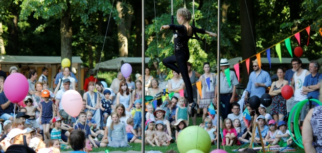 Eine junge Akrobatin führt im Freien vor einer sitzenden Menschenmenge Kunststücke auf.