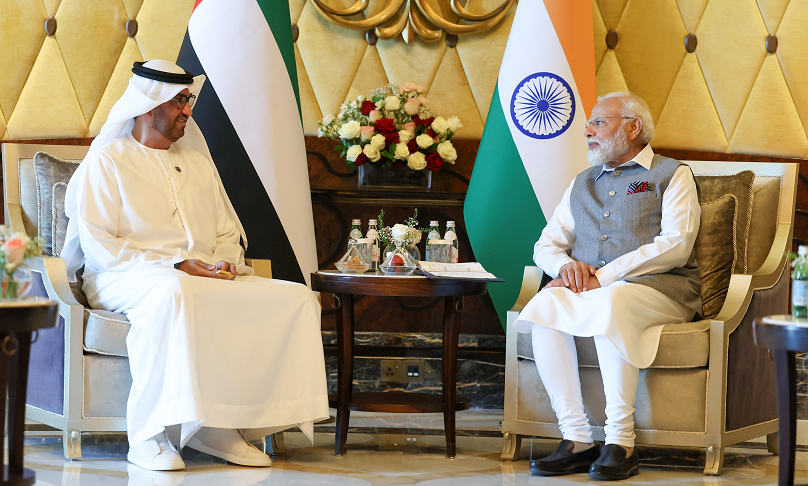 Der indische Premierminister Modi und der designierte COP 28 Präsident und CEO der Abu Dhabi National Oil Company Al Jaber sitzen vor Flaggen ihrer Staaten und unterhalten sich. 