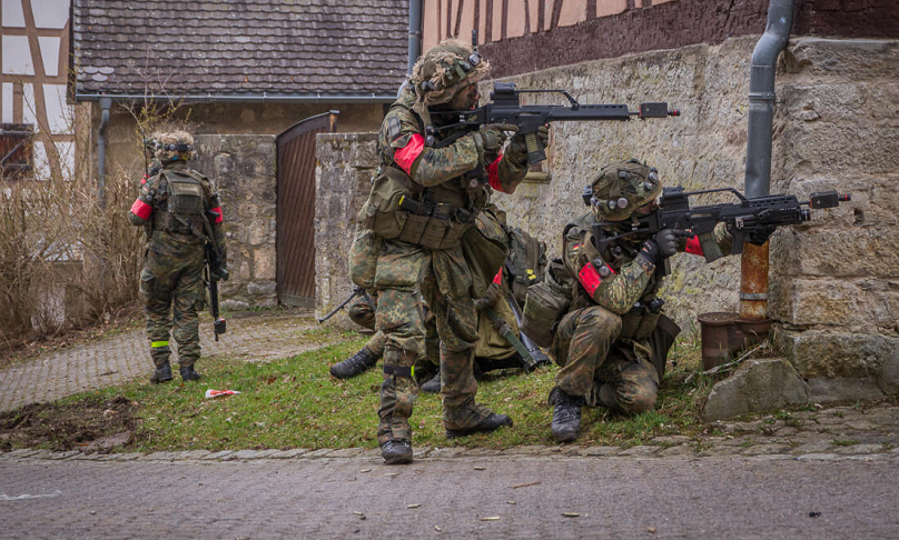 Soldaten der Bundeswehr mit roten Armbändern bei einer Übung auf dem Truppenübungsplatz